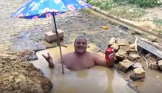 Morador toma banho dentro de buraco em rua do bairro Santa Clara.