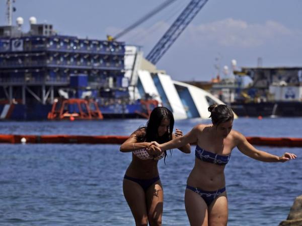 Banhistas caminham sobre pedras próximo ao local onde o Costa Concordia encalhou, na ilha toscana de Isola del Giglio(Imagem:Reprodução) Banhistas caminham sobre pedras próximo ao local onde o Costa Concordia encalhou, na ilha toscana de Isola del Giglio(Imagem:Reprodução)
