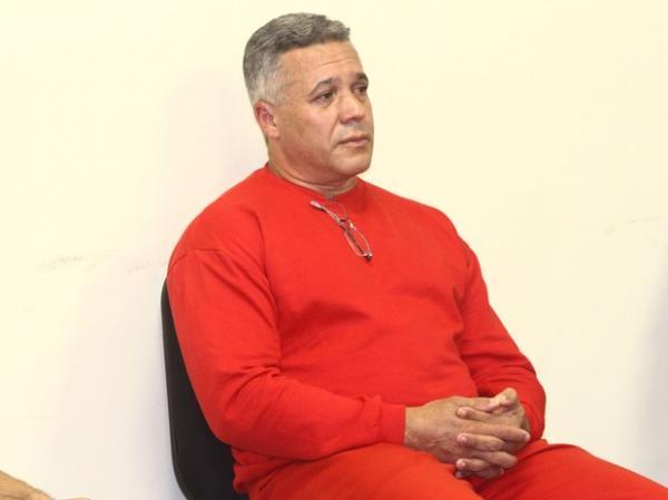 Bola está vestido com o uniforme vermelho da Subsecretaraia de Administração Prisional (Suapi). Na gola do moleton, ele carrega óculos de grau. (Imagem:Reprodução) Bola está vestido com o uniforme vermelho da Subsecretaraia de Administração Prisional (Suapi). Na gola do moleton, ele carrega óculos de grau. (Imagem:Reprodução)
