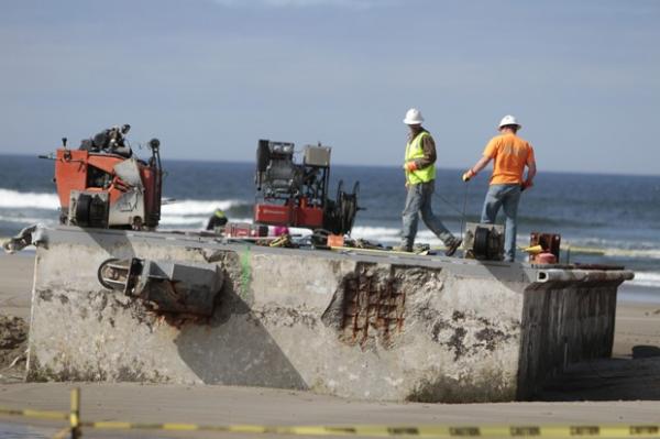 Homens começam a trabalhar na retirada de doca na praia de Agate, ao sudoeste da cidade de Portland (Imagem:Randy L. Rasmussen/AP) Homens começam a trabalhar na retirada de doca na praia de Agate, ao sudoeste da cidade de Portland (Imagem:Randy L. Rasmussen/AP)
