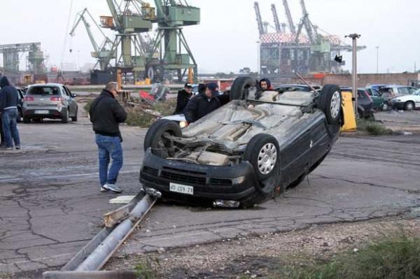 Homens observam carro capotado por fenômeno em Taranto nesta quarta-feira(Imagem:Reprodução) Homens observam carro capotado por fenômeno em Taranto nesta quarta-feira(Imagem:Reprodução)